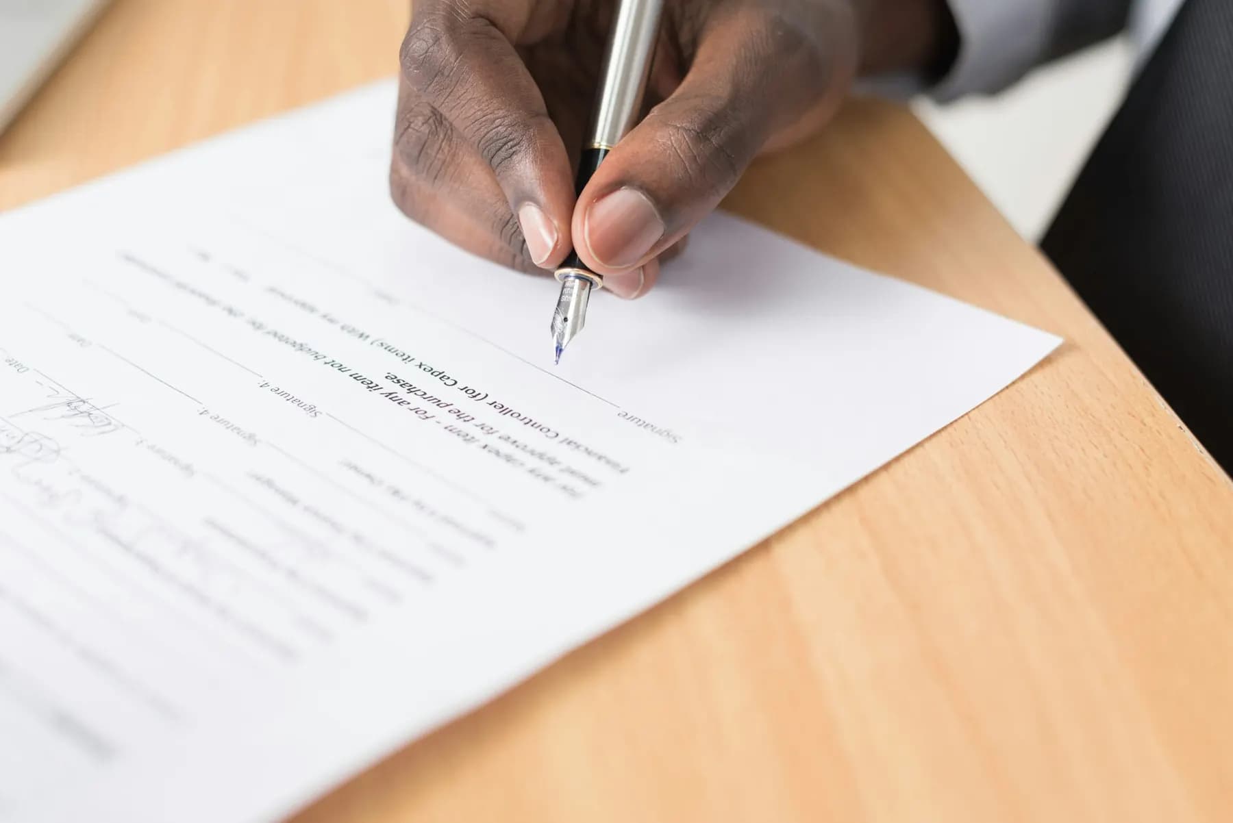 A hand signing a document with a pen